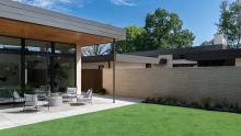 Covered seating area in backyard with adjacent residence in background.